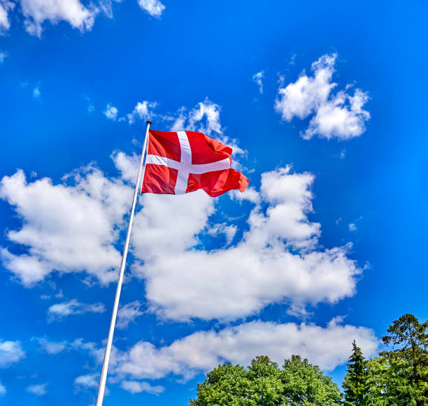 istock denmark flag in the wind with blue sky and clouds. 1166583068