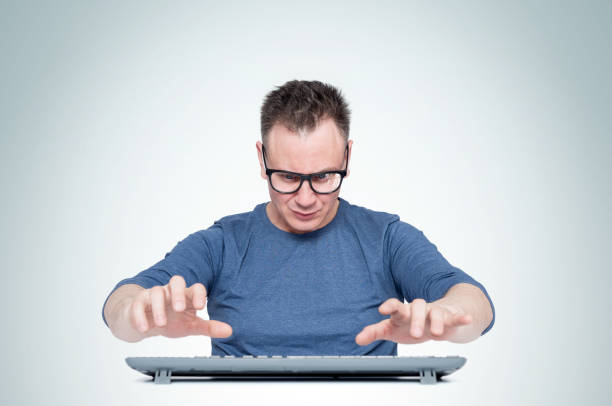 istock Man in glasses working at the computer, his hands hover over the keyboard while typing, on light background. Front view. 1166584115