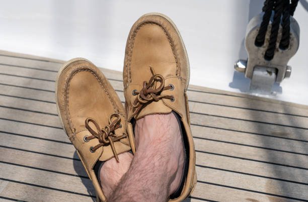 Man wearing boes shoes on sailboat deck stock photo