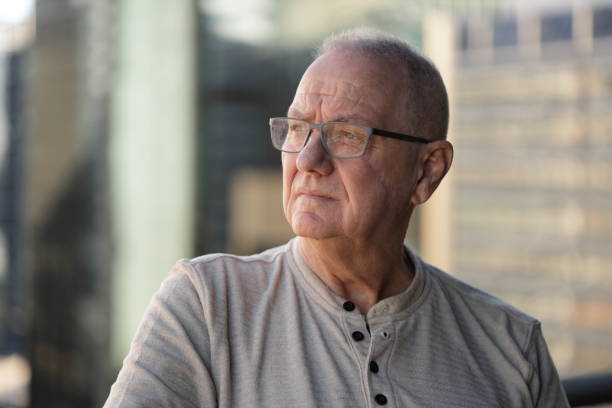 Senior man remembering Senior man with facial scar looking to the side. Out of focus office buildings in the background. profile view photos stock pictures, royalty-free photos & images