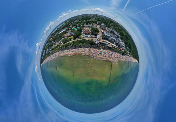 istock Drone aerial panoramic 360 degree view on sunny beach with sunbathers with windbreaks and towels at sea in touristic city 1166588784