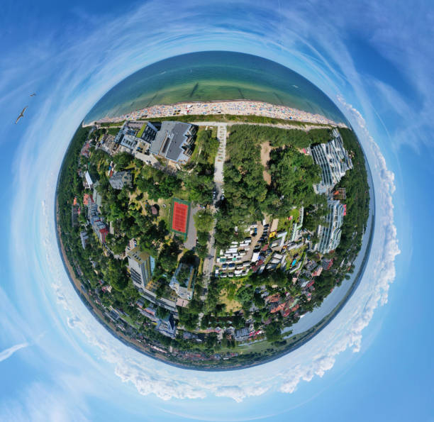 istock Drone aerial panoramic 360 degree view on sunny beach with sunbathers with windbreaks and towels at sea in touristic city 1166589016