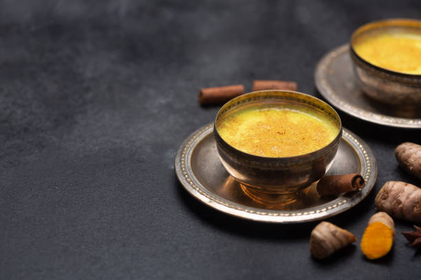 istock Golden turmeric milk on the black background with ingredients 1166593137