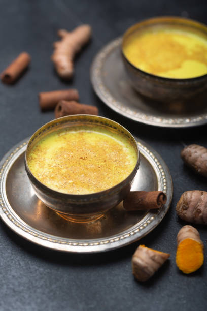 istock Golden turmeric milk on the black background with ingredients 1166593150