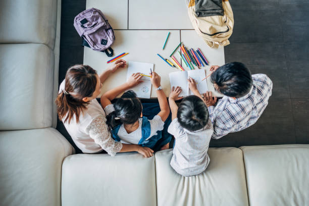 Parents doing homework with daughter and son at home Group of people, parents doing homework with two children together at home. homework stock pictures, royalty-free photos & images