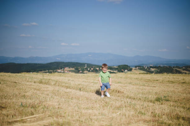 Happy young boy playing outdoors in summer meadow