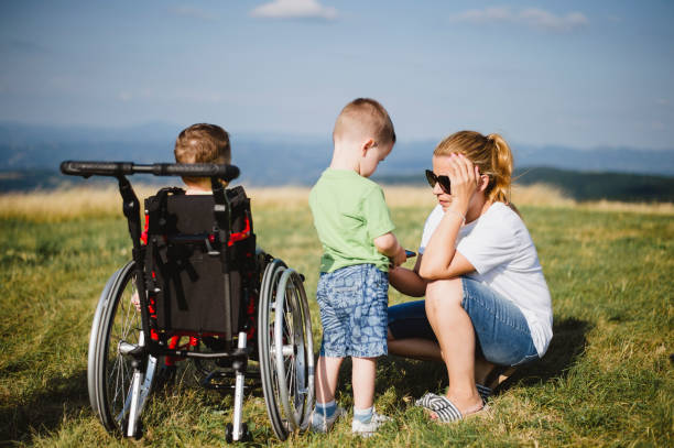 istock Mother crouching by son in wheelchair at field 1166599459