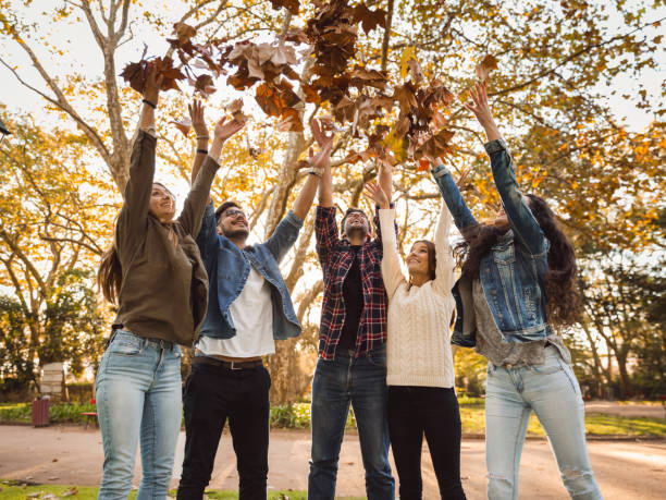 istock Friends having fun throwing leaves in the air 1166600853