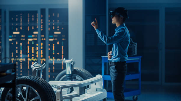 ingénieur automobile travaillant sur la plate-forme de châssis de voiture électrique, utilisant le casque de réalité augmentée avec des gestures touchants. dans l'installation de laboratoire d'innovation concept vehicle frame comprend roues, suspensi - electric motor audio photos et images de collection