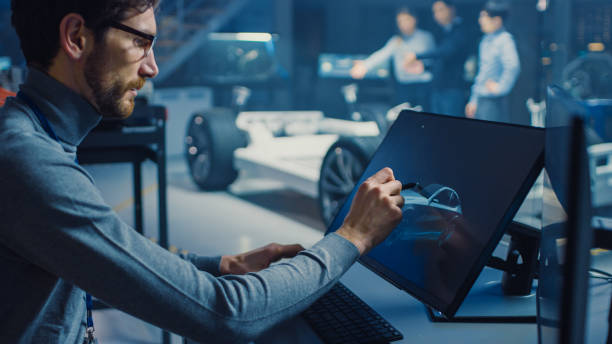istock Professional Automotive Graphic Designer is Working on Concept Car Render with a Stylus Pen in a High Tech Innovative Laboratory with a Prototype Car Chassis. 1166603997