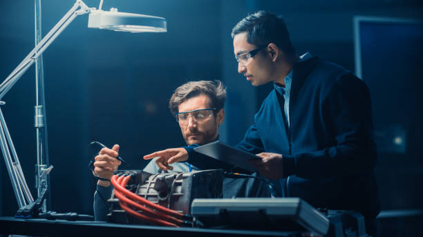 istock Two Professional Automotive Engineers with a Tablet Computer and Inspection Tools are Having a Conversation While Testing an Electric Engine in a High Tech Laboratory with a Concept Car Chassis. 1166604671