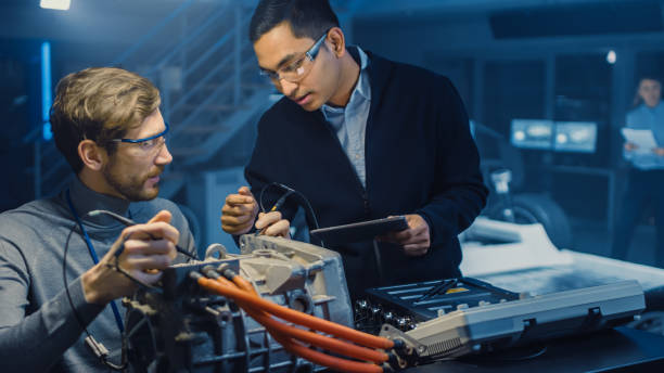istock Two Professional Automotive Engineers with a Tablet Computer and Inspection Tools are Having a Conversation While Testing an Electric Engine in a High Tech Laboratory with a Concept Car Chassis. 1166605300