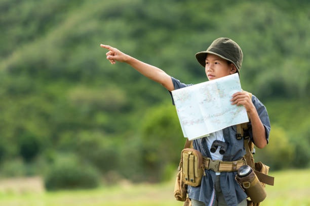 istock Asian boy backpack checking map and pointing in jungle forest, trips adventure and tourism for destination and leisure for education and relax in nature park .  Travel vacations Concept 1166608650