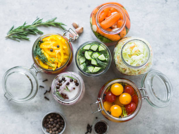 Pickled vegetables. Salting various vegetables in glass jars for long-term storage. Preserves vegetables in glass jars. Variety fermented green vegetables on table. stock photo