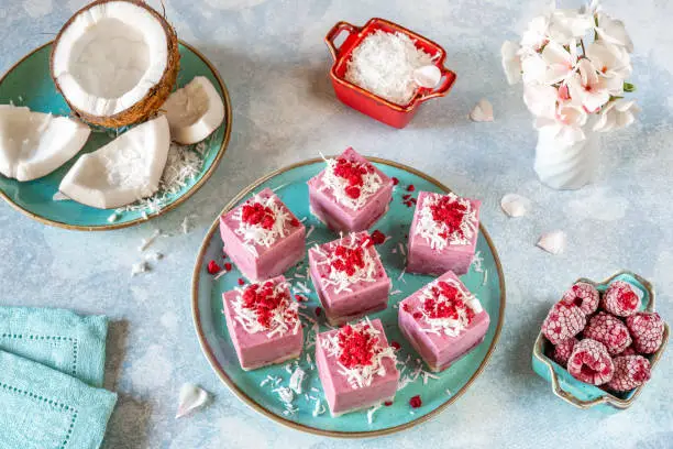 Fermented cashew mousse cakes with raspberry jam, decorated with coconut flakes and sublimated raspberries. Raw-vegan, gluten-free, no eggs. Healthy eating concept.