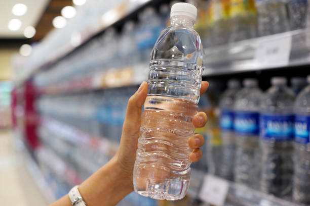 Hand holding a bottle of drinking water in grocery store stock photo