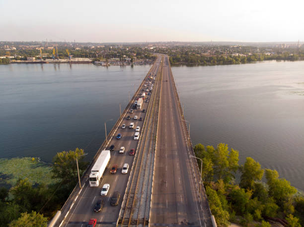 View from the drone to heavy traffic on a bridge over a river. View from the drone to heavy traffic on a bridge over a river with a view of the city in the distance. filming point of view highway day road stock pictures, royalty-free photos & images