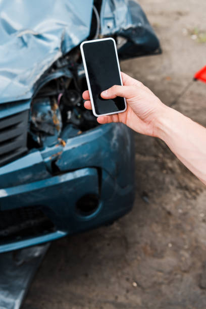 istock selective focus of man holding smartphone with blank screen near crashed car 1166617363