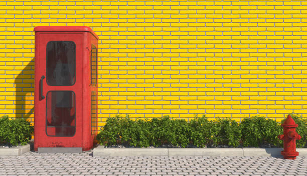una antigua cabina telefónica roja de estilo retro en el sendero en el exterior urbano frente a la fachada de la pared de ladrillo amarillo y la boca de incendios roja. renderizado 3d. - telephone cabin fotografías e imágenes de stock