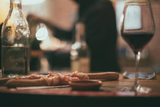 Happy Hour At The Local Pub Serano ham, finger bread and a nice glass of red. Defocused pub action on background. wine bar counter stock pictures, royalty-free photos & images