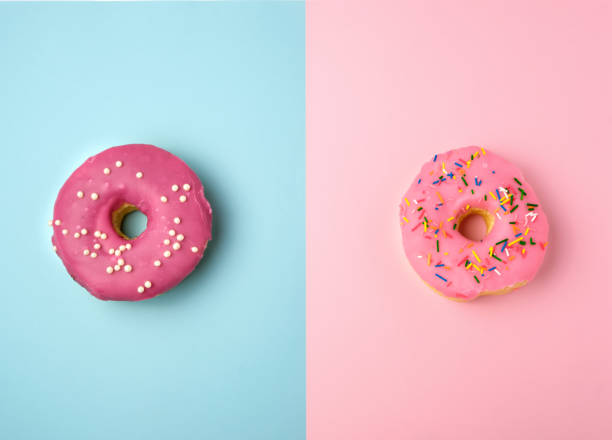 istock two whole round pink donuts with colored sprinkles lie on a blue-pink background 1166620701