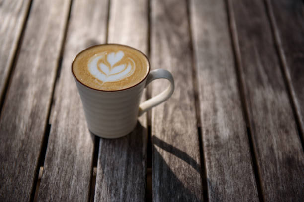 Heart shape coffee art in white cup on wooden table