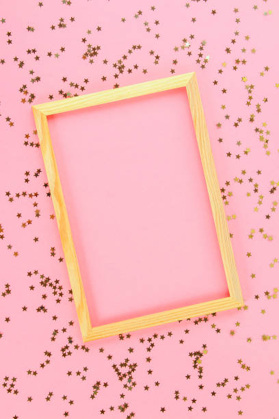 istock A wooden empty frame on a pastel background surrounded by shiny decorative stars and balls. 1166622279