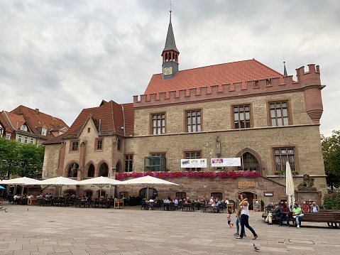 Göttingen, Germany - August, 1 - 2019: View of the old town hall at the market square. People sitting on benches, in restaurants, walking around and enjoying this summer day.