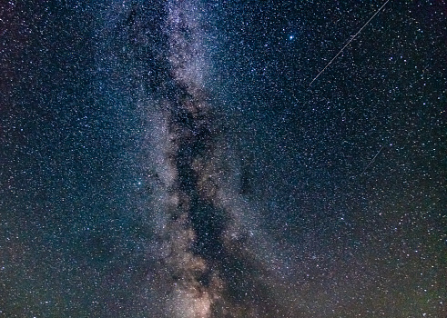 A long exposure image of the Milky Way with satellite over Vault beach, Cornwall in summer