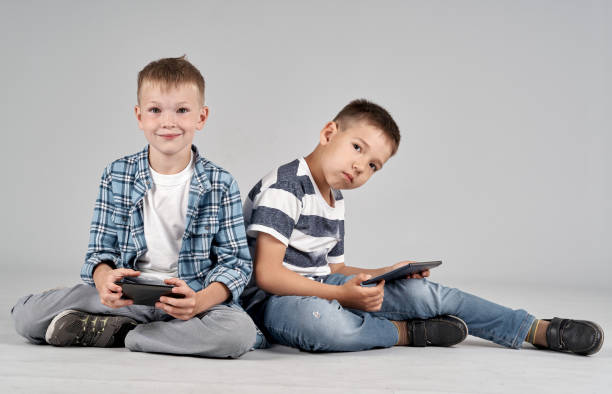 istock Two Little Friends Are Playing At Games On Mobile Devices 1166627575