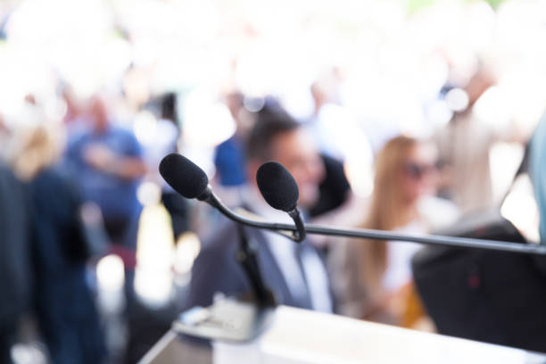 istock Microphone in focus at media or public event, blurred people in the background 1166630707