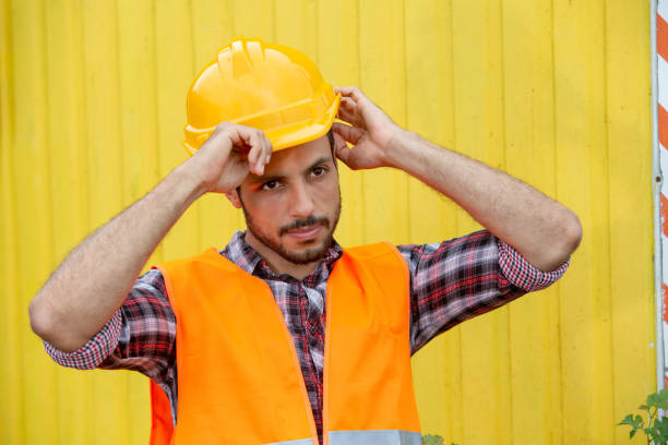 istock handsome construction worker with yellow helmet and orange vest 1166633198