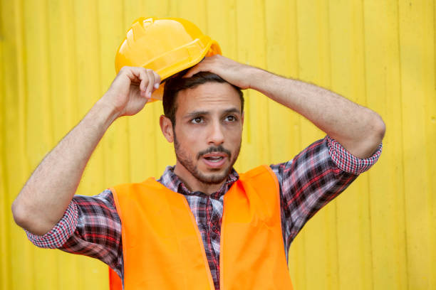 construction worker with yellow helmet and orange vest looking surprised