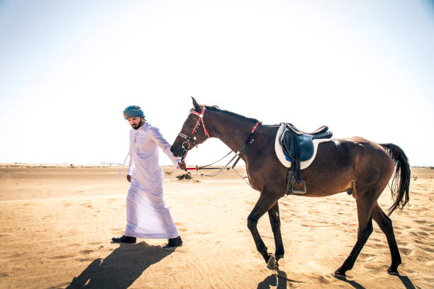istock Arabian man with horse in the desert 1166635149