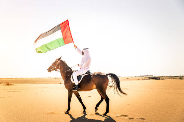 Arabian man with horse in the desert Middle eastern handsome man with typical emirates dress riding a arabic horse in the Dubai desert arab man riding horse stock pictures, royalty-free photos & images