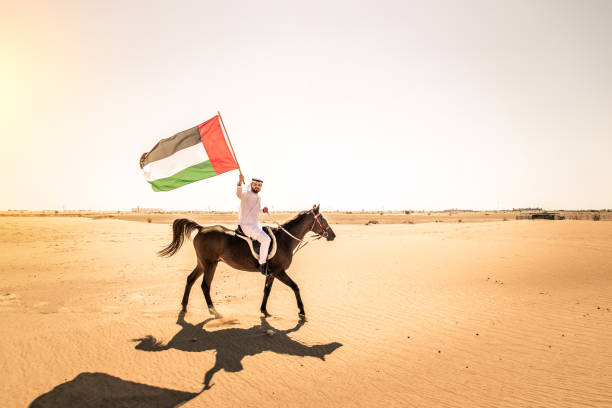 Arabian man with horse in the desert Middle eastern handsome man with typical emirates dress riding a arabic horse in the Dubai desert arab man riding horse stock pictures, royalty-free photos & images
