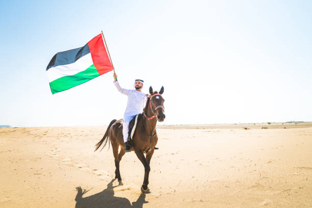 Arabian man with horse in the desert Middle eastern handsome man with typical emirates dress riding a arabic horse in the Dubai desert arab man riding horse stock pictures, royalty-free photos & images