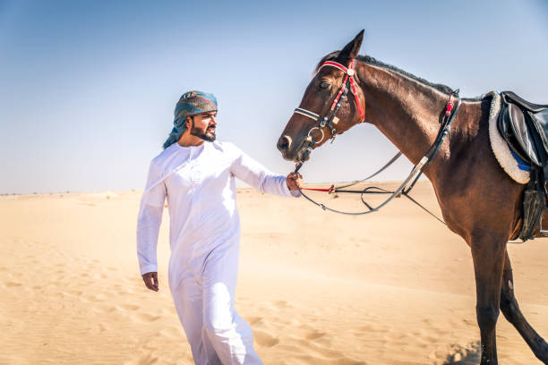 istock Arabian man with horse in the desert 1166636391