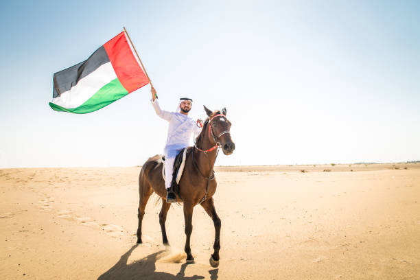 Arabian man with horse in the desert Middle eastern handsome man with typical emirates dress riding a arabic horse in the Dubai desert arab man riding horse stock pictures, royalty-free photos & images