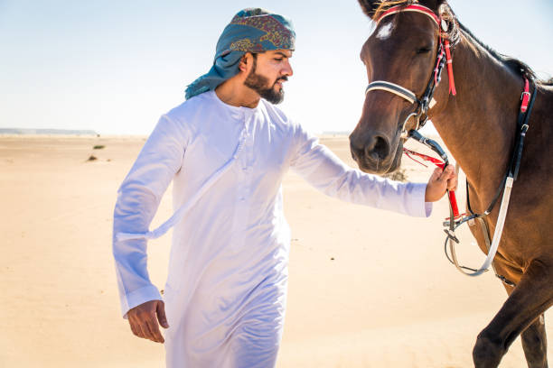 istock Arabian man with horse in the desert 1166636598