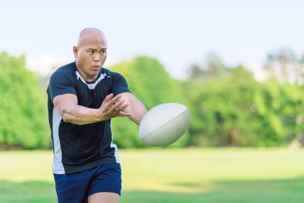 Rugby player passing ball to team-mate A rugby player is passing a rugby ball to a team-mate. skin head stock pictures, royalty-free photos & images