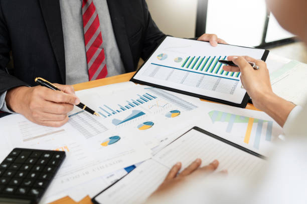 istock Midsection Of Coworkers Discussing Graphs In Office 1166648178