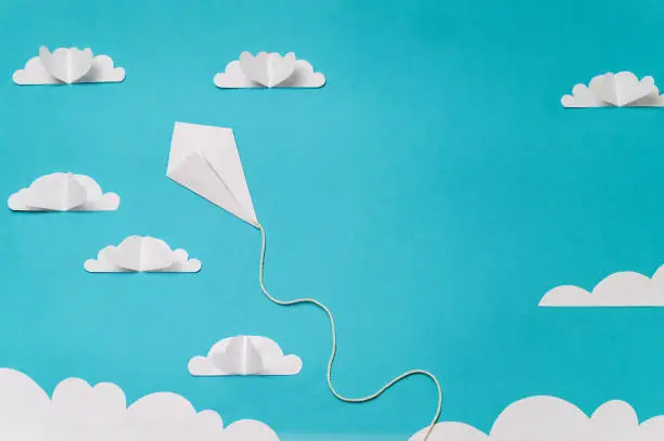 Photo of Origami kite in sky with clouds. Creative concept for banner/landing/background designs.