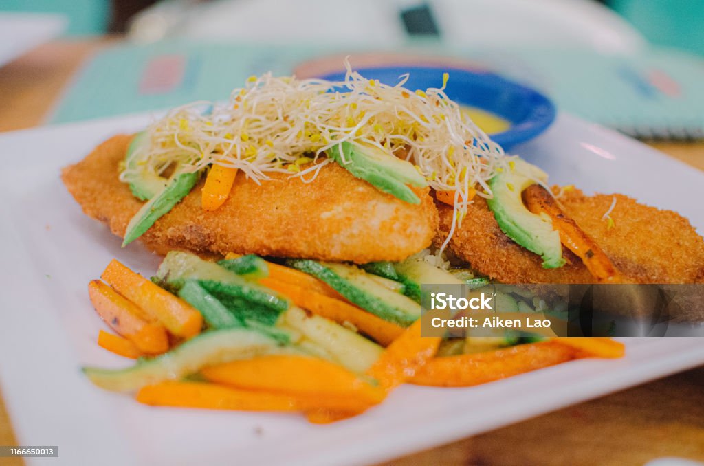 Fried Fish with Vegetables Breaded, fried fish with baked veggies and avocado. Close-up Stock Photo