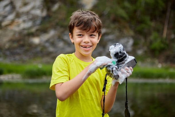 istock Joyful naughty boy washes a camera, destroying it. 1166650634