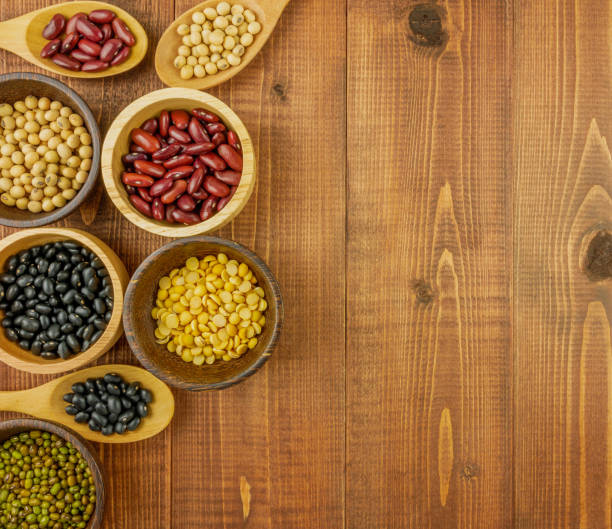 Flat lay,top view assorted beans including red bean,soybeans,black beans,mung beans on brown,beige wooden background with copy space
