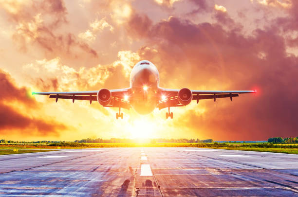 istock Airplane lands on runway with landing lights on during a bright rays sunset, with beautiful clouds. 1166662107