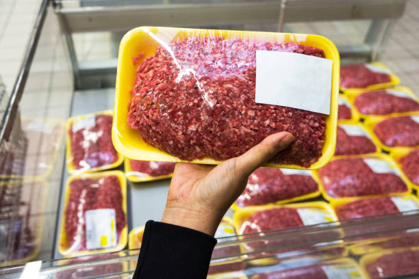Buyer woman chooses chopped meat in market stock photo