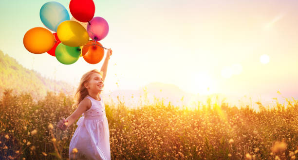 niño feliz corriendo con globos en el campo al atardecer - child balloon happiness cheerful fotografías e imágenes de stock