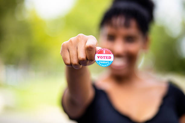 Young Black Woman with I Voted Sticker A young black woman holds an I Voted sticker midterm election photos stock pictures, royalty-free photos & images